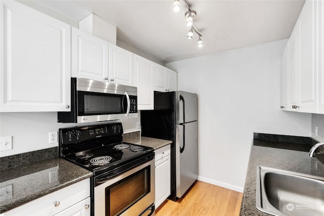 kitchen with white cabinets, light hardwood / wood-style floors, sink, rail lighting, and stainless steel appliances