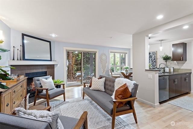 living room with sink, a tiled fireplace, and light wood-type flooring