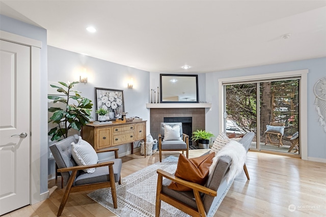 sitting room with a tiled fireplace and light hardwood / wood-style flooring