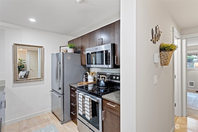 kitchen featuring light hardwood / wood-style floors, dark brown cabinetry, and stainless steel appliances