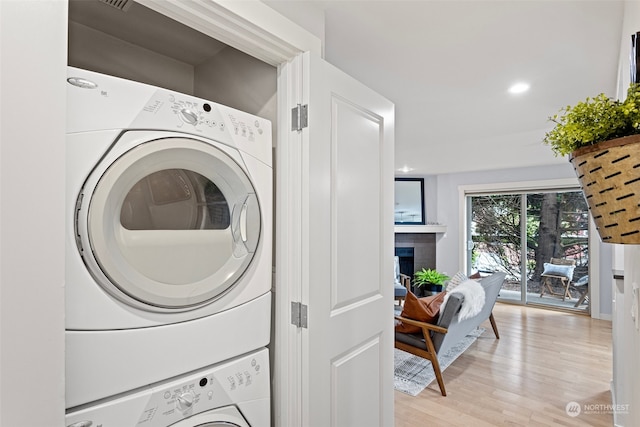 washroom with stacked washer and dryer and light wood-type flooring