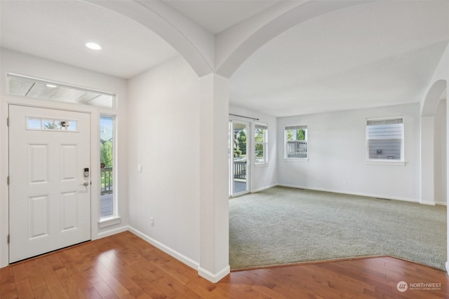 foyer entrance with arched walkways, recessed lighting, baseboards, and wood finished floors