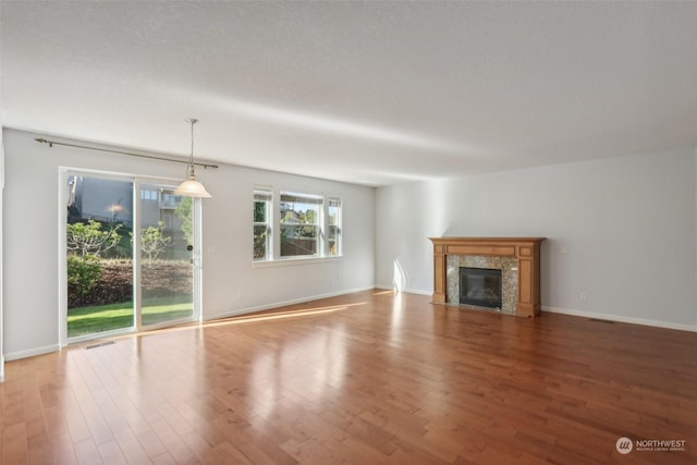 unfurnished living room featuring light wood-type flooring, a premium fireplace, and baseboards