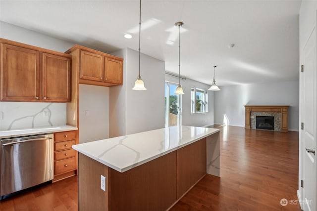 kitchen with dark wood-style flooring, brown cabinets, hanging light fixtures, light stone countertops, and dishwasher