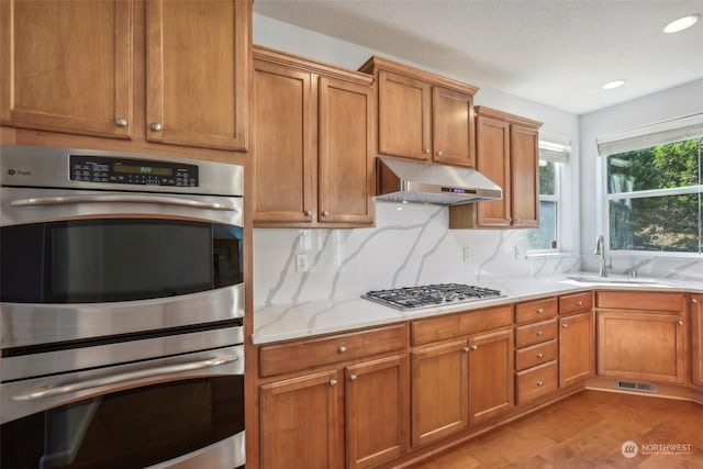 kitchen with under cabinet range hood, a sink, visible vents, appliances with stainless steel finishes, and tasteful backsplash