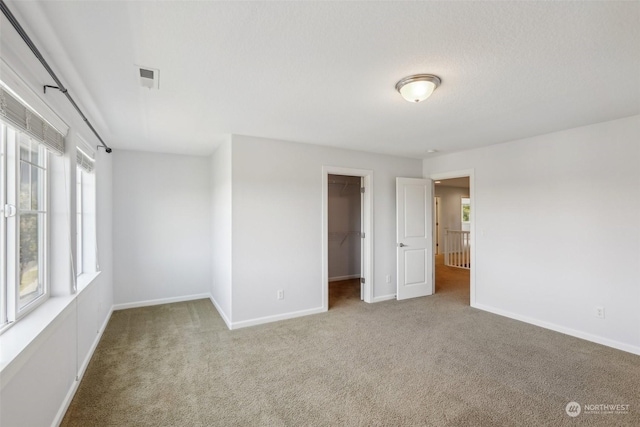 carpeted empty room featuring visible vents and baseboards