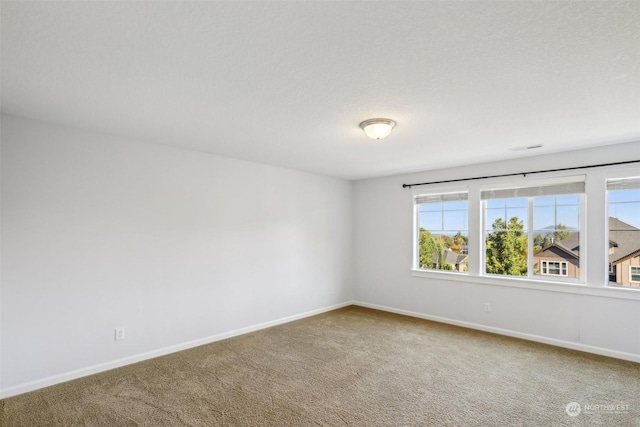 spare room with carpet, a textured ceiling, and baseboards