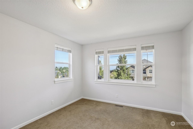 unfurnished room featuring baseboards, a textured ceiling, visible vents, and carpet flooring