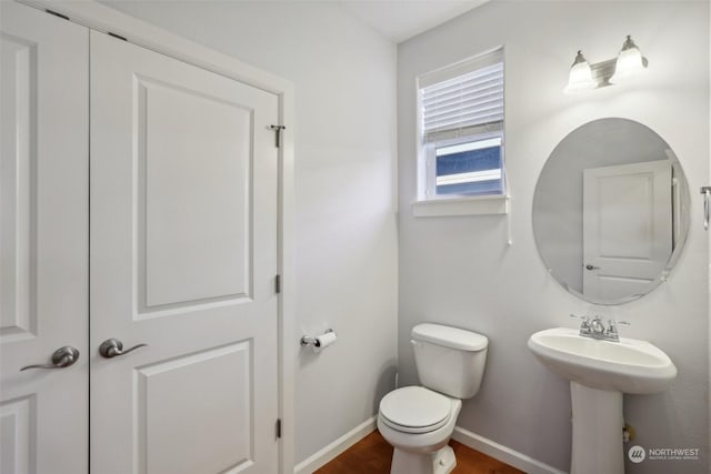 bathroom with wood finished floors, a sink, toilet, and baseboards