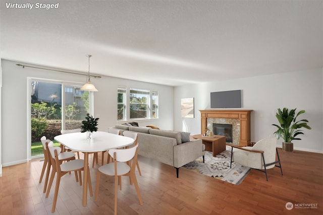 dining space with baseboards, light wood finished floors, and a premium fireplace