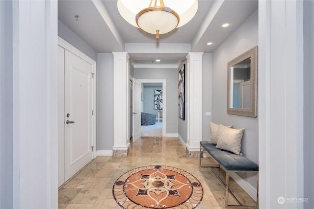 hallway featuring light tile patterned flooring, a raised ceiling, and decorative columns