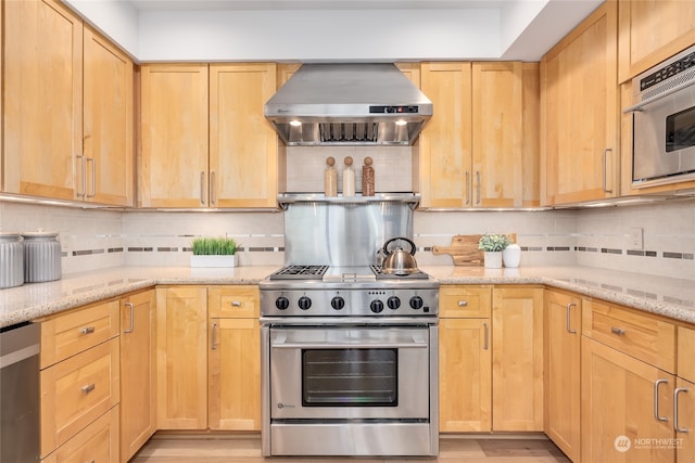 kitchen with wall chimney exhaust hood, backsplash, light hardwood / wood-style floors, and stainless steel appliances