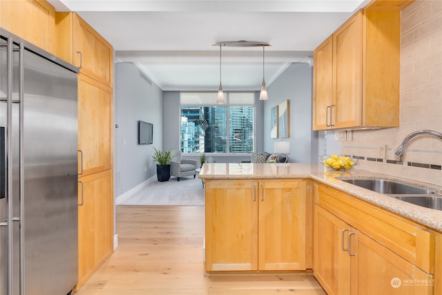 kitchen featuring ornamental molding, sink, light wood-type flooring, high quality fridge, and kitchen peninsula