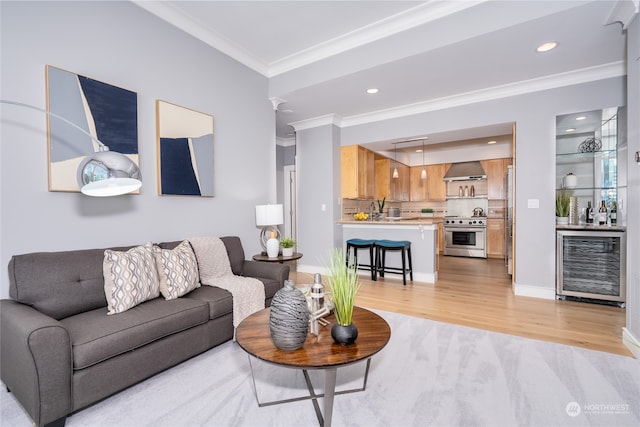 living room with sink, light hardwood / wood-style flooring, crown molding, and wine cooler