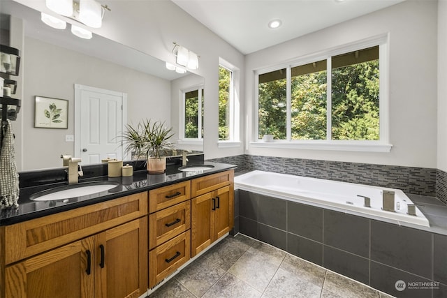 bathroom with vanity and tiled tub