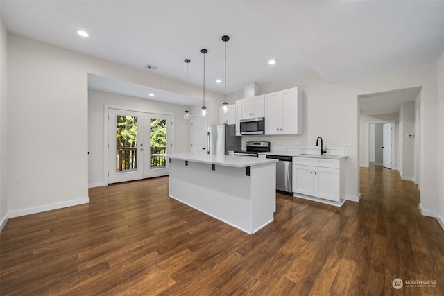 kitchen featuring white cabinets, french doors, appliances with stainless steel finishes, dark hardwood / wood-style flooring, and a kitchen island