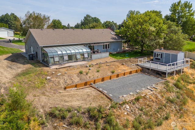 rear view of property with a storage unit and a deck