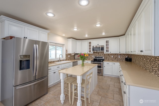 kitchen featuring sink, white cabinetry, tasteful backsplash, a kitchen island, and stainless steel appliances