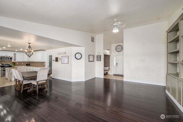 dining space featuring lofted ceiling, ceiling fan with notable chandelier, and dark hardwood / wood-style floors