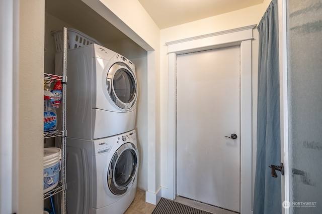 laundry room with stacked washer / drying machine and light tile patterned floors