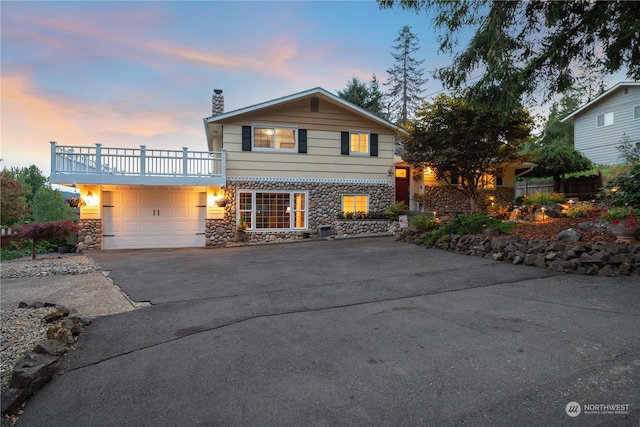 view of front of house with a garage, stone siding, driveway, and a chimney