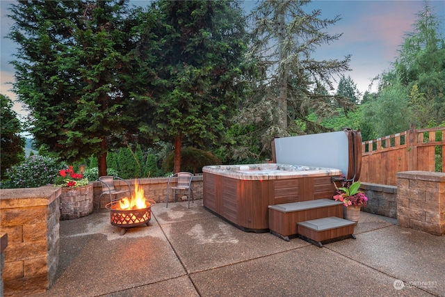 patio terrace at dusk with an outdoor fire pit and a hot tub