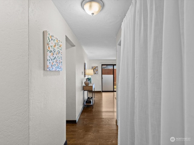 corridor featuring wood finished floors and a textured wall