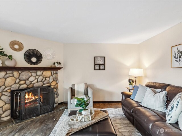 living area with a stone fireplace, wood finished floors, and baseboards
