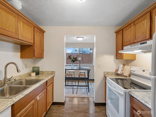kitchen with under cabinet range hood, brown cabinets, white electric stove, a textured ceiling, and a sink