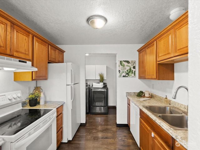 kitchen with white appliances, brown cabinetry, separate washer and dryer, a sink, and under cabinet range hood