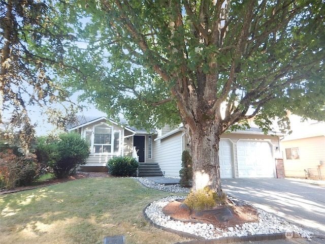 view of front of property featuring a front lawn, concrete driveway, and an attached garage