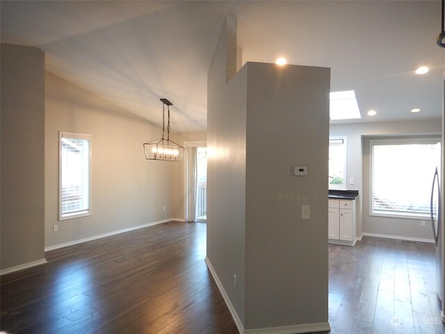 hall featuring vaulted ceiling with skylight, a chandelier, and dark hardwood / wood-style flooring