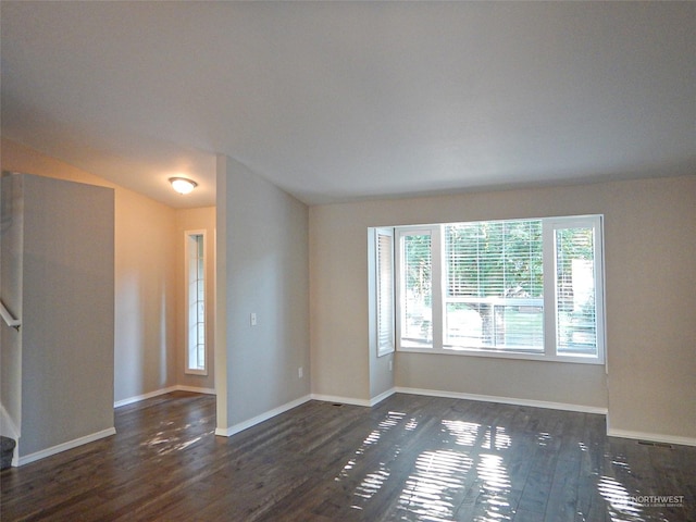 spare room featuring dark wood-type flooring and baseboards