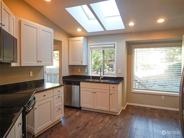 kitchen featuring dark countertops, white cabinetry, dishwasher, and a sink