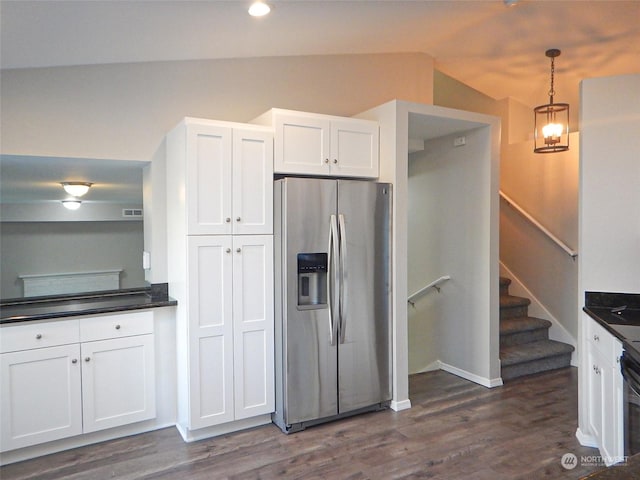 kitchen featuring lofted ceiling, dark countertops, stainless steel fridge, and white cabinetry