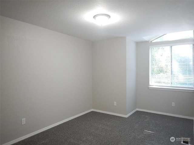 unfurnished room with dark colored carpet and baseboards