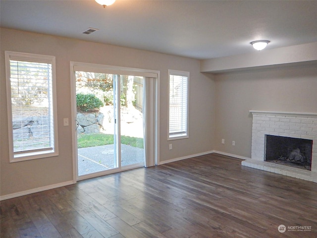 unfurnished living room featuring a fireplace, dark wood finished floors, visible vents, and baseboards