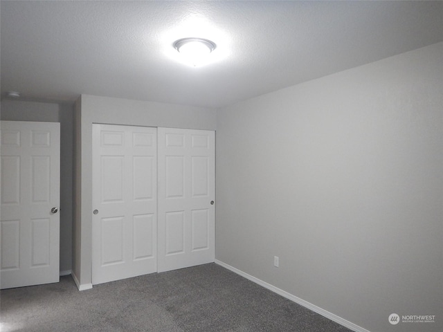 unfurnished bedroom with a textured ceiling, carpet floors, a closet, and baseboards