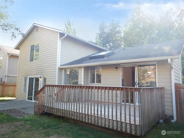 back of house with roof with shingles, fence, and a wooden deck