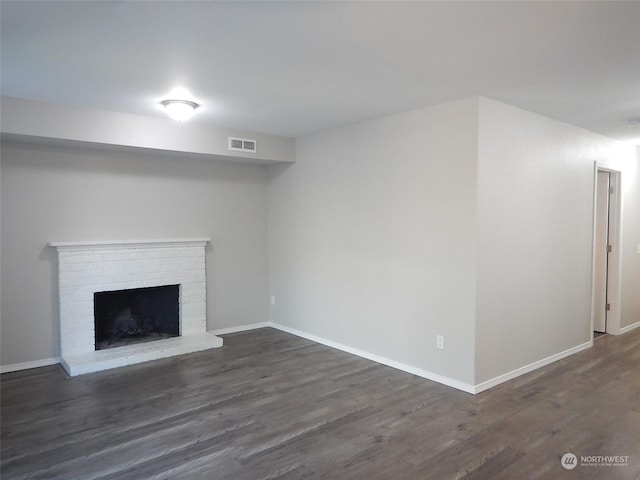 unfurnished living room featuring baseboards, a fireplace, visible vents, and dark wood finished floors