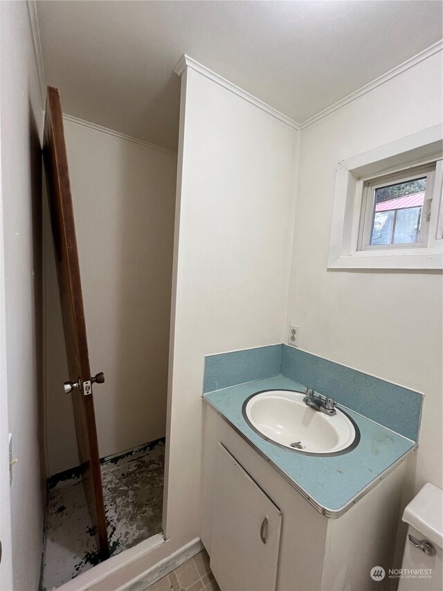 bathroom with tile patterned flooring, crown molding, toilet, and vanity