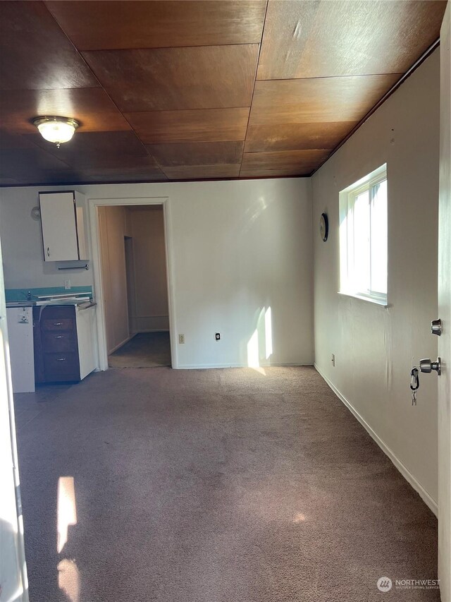 unfurnished living room with carpet flooring and wooden ceiling