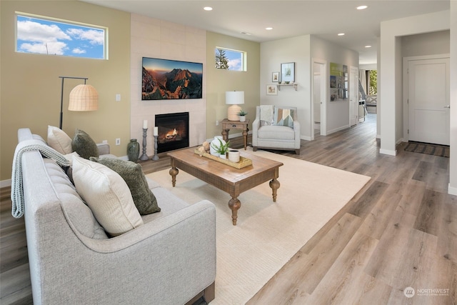 living room featuring a tiled fireplace and light wood-type flooring