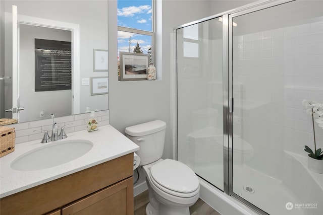 bathroom with hardwood / wood-style floors, toilet, walk in shower, and vanity