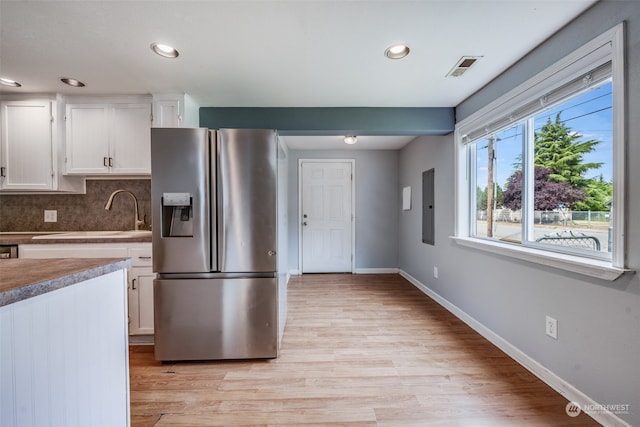 kitchen with light hardwood / wood-style floors, stainless steel fridge with ice dispenser, sink, tasteful backsplash, and white cabinetry