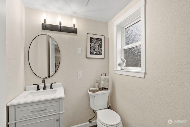 bathroom with a textured ceiling, toilet, and vanity