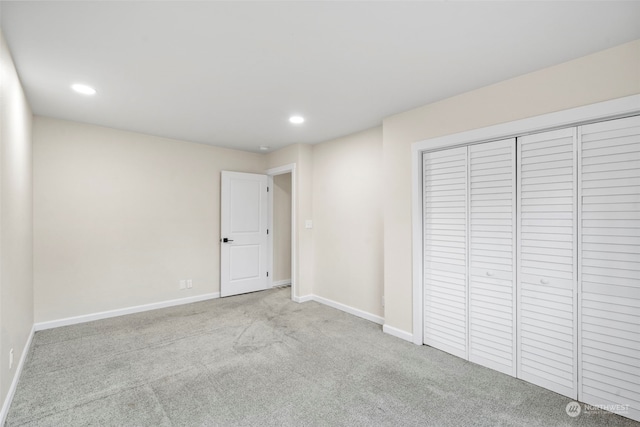 unfurnished bedroom featuring a closet and light colored carpet