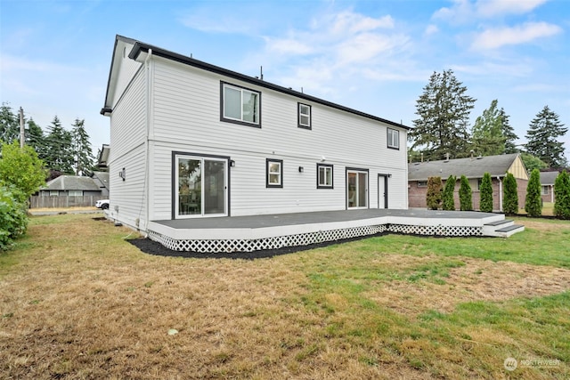 back of house featuring a wooden deck and a lawn