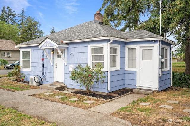 bungalow-style home featuring entry steps, a shingled roof, and a chimney