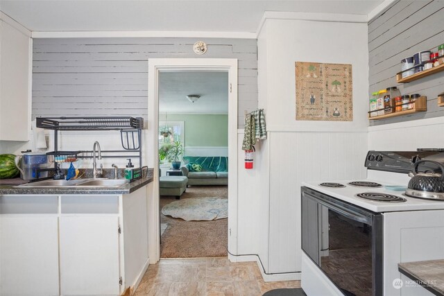 kitchen with light tile patterned floors, white cabinets, sink, and white range with electric cooktop